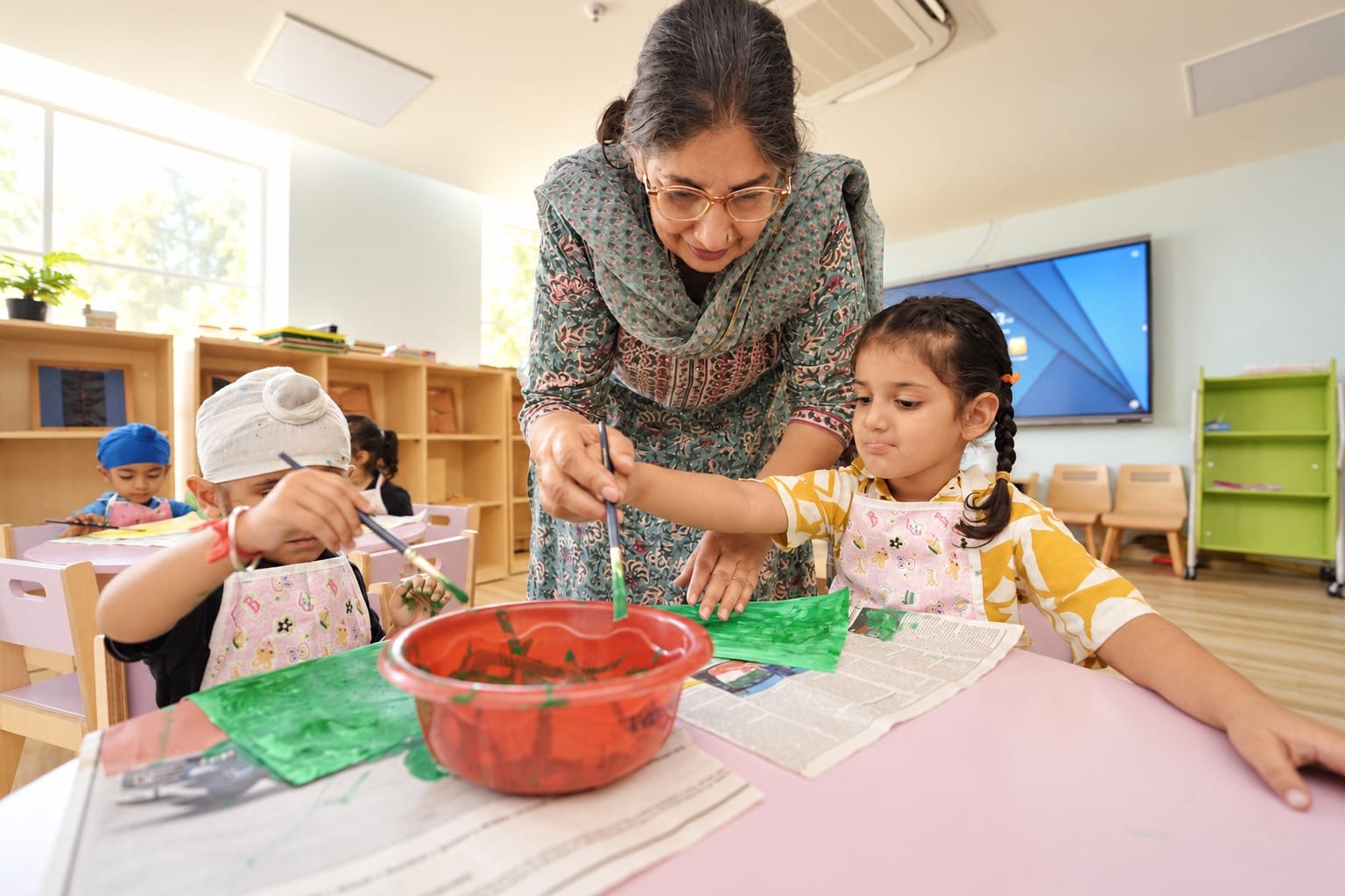 A teacher mixing paint with two children